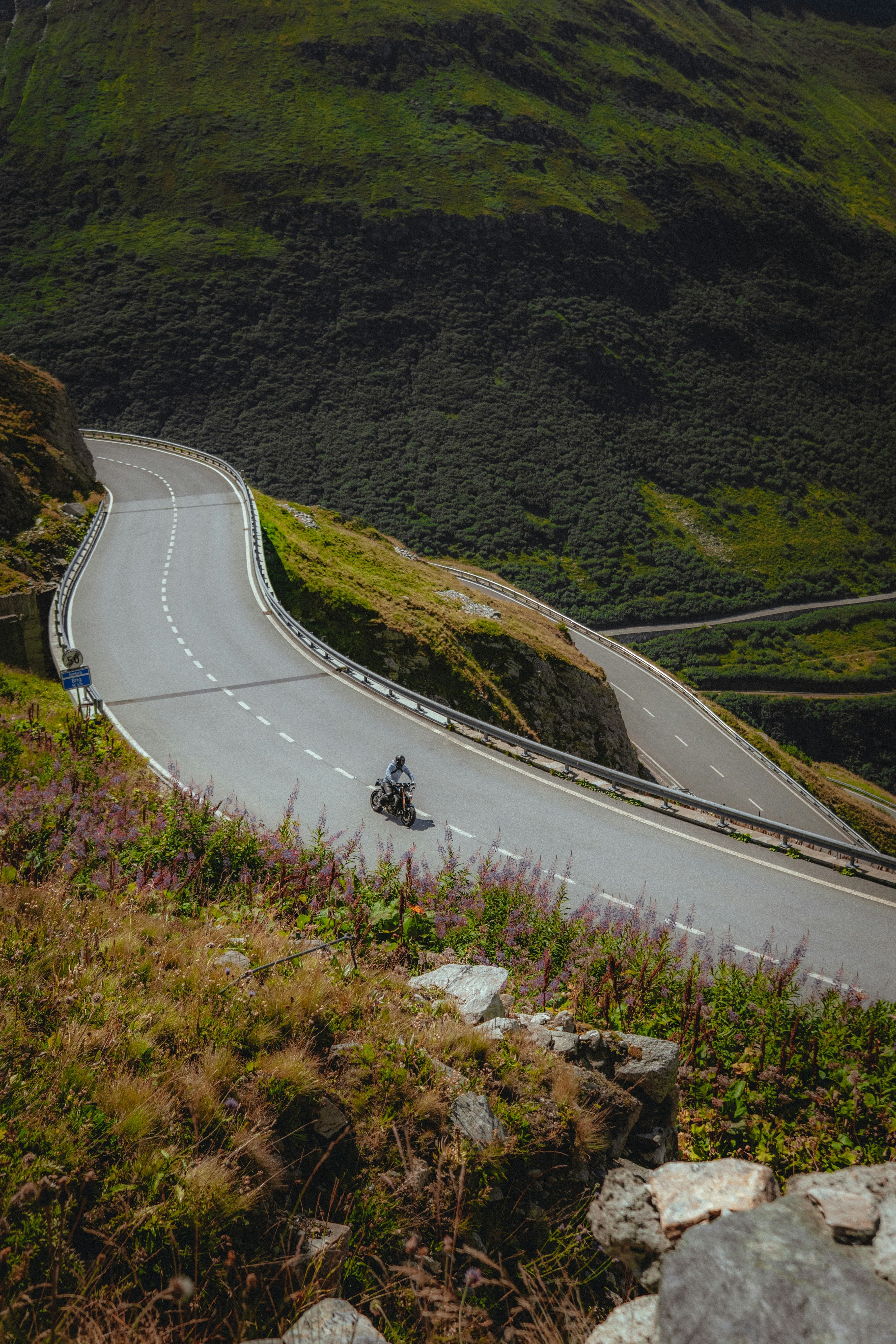 Switchback road climbing a green mountainside