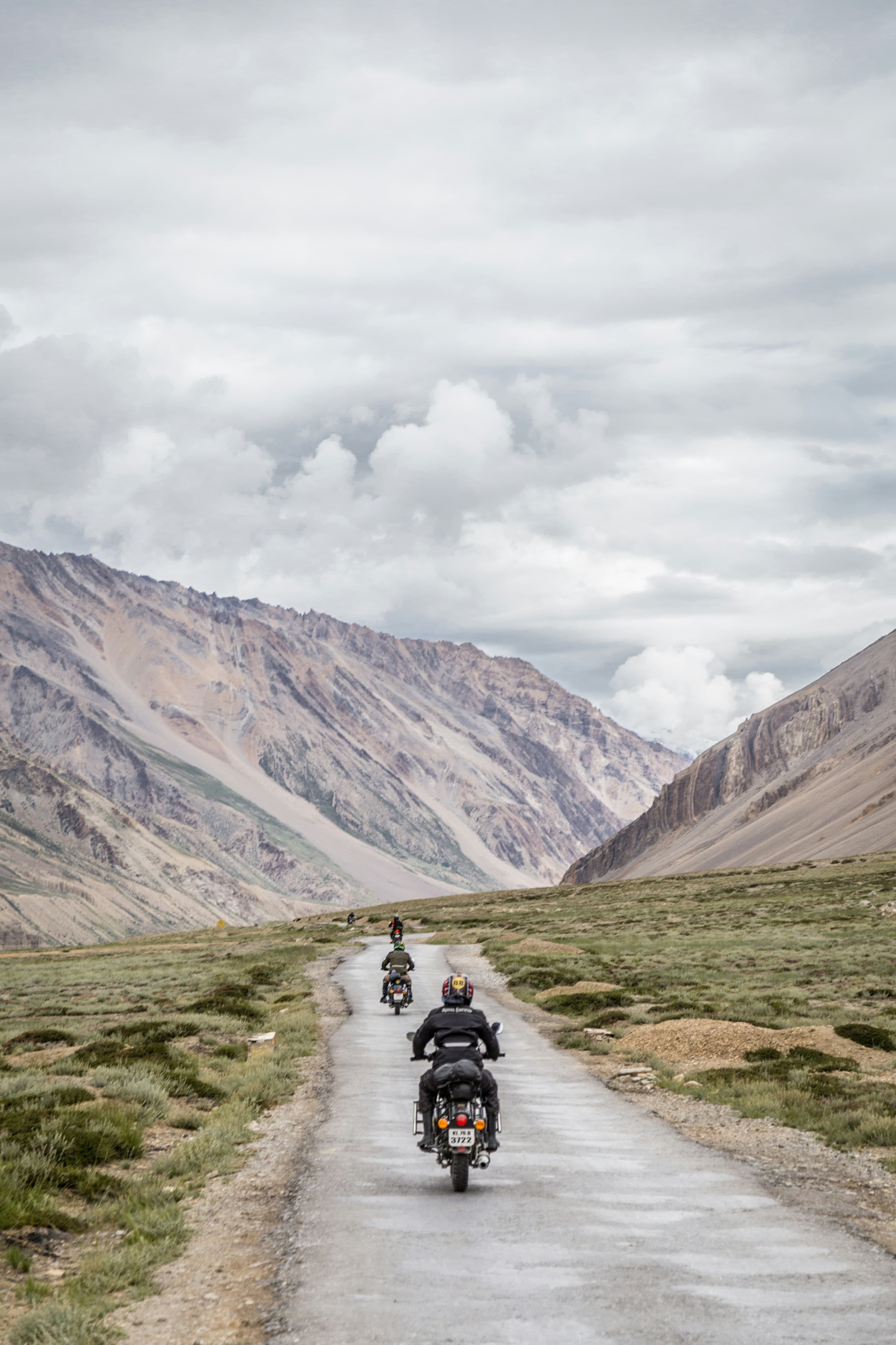 A line of bikes riding a narrow road through a wide open mountain valley