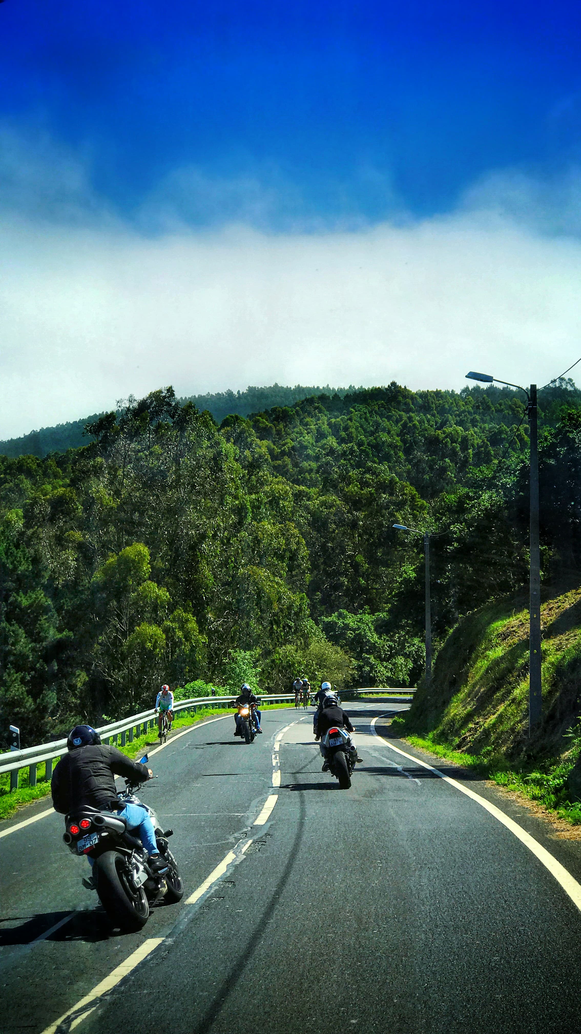Riders dropping down a mountain road into cloud