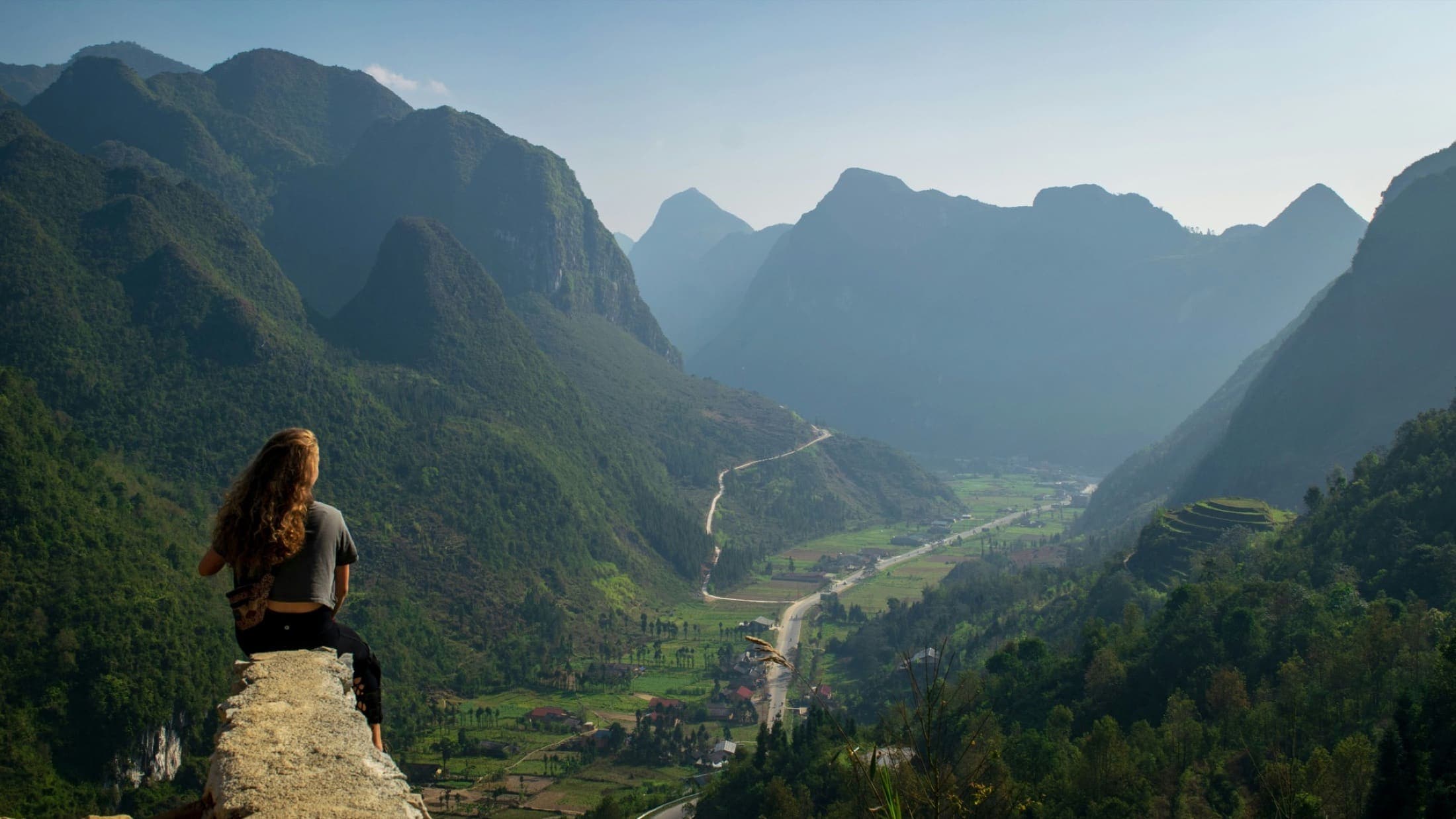 A motorcycle rider looking across the mountain landscape in Ha Giang