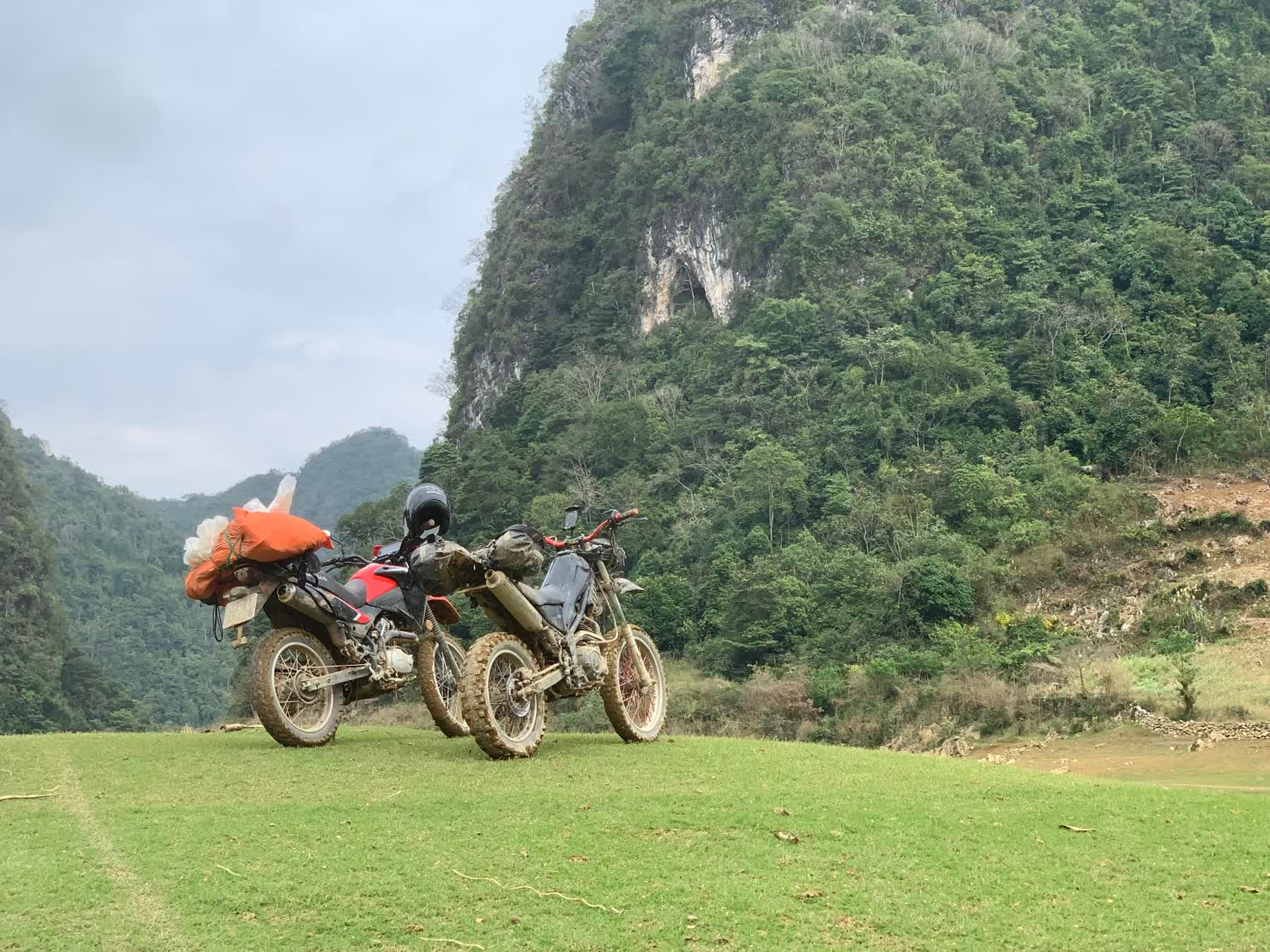Dirt bikes parked below a limestone cliff in Northern Vietnam