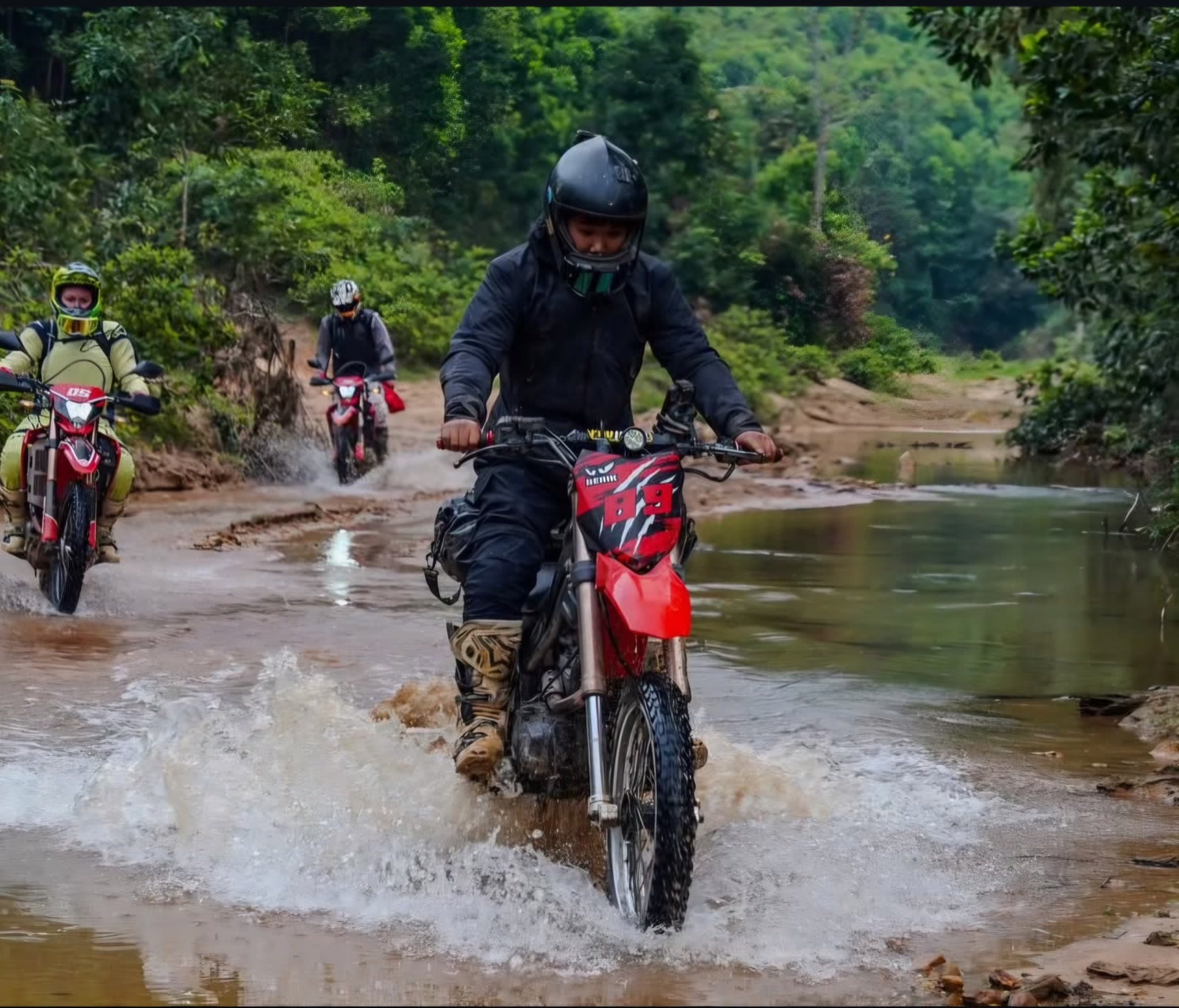 Dirt bike riders crossing water on a forest trail